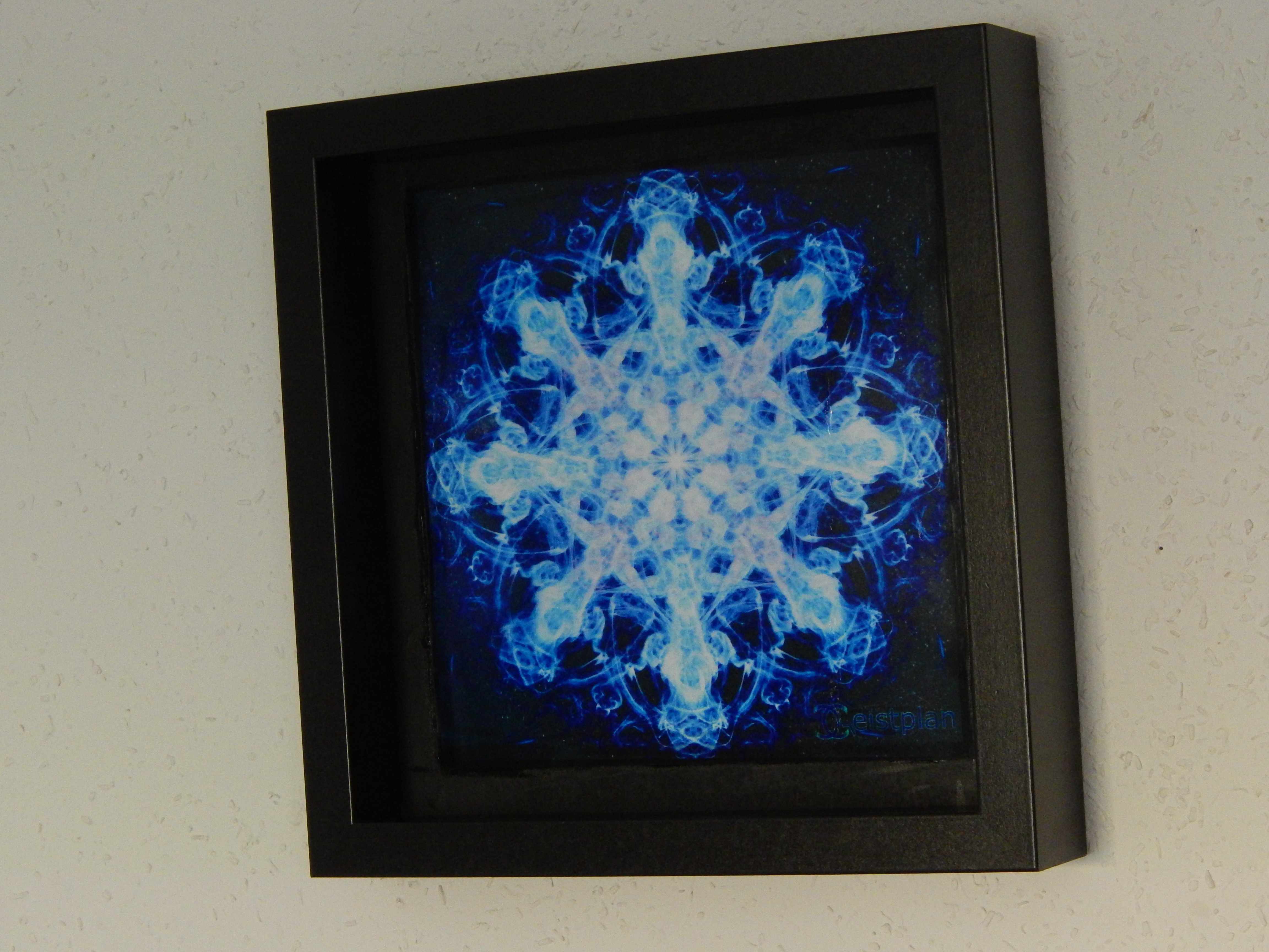 Blau leuchtendes psychodelisches Mandala in einem Objektrahmen. Kräftige blau leuchtende Farben