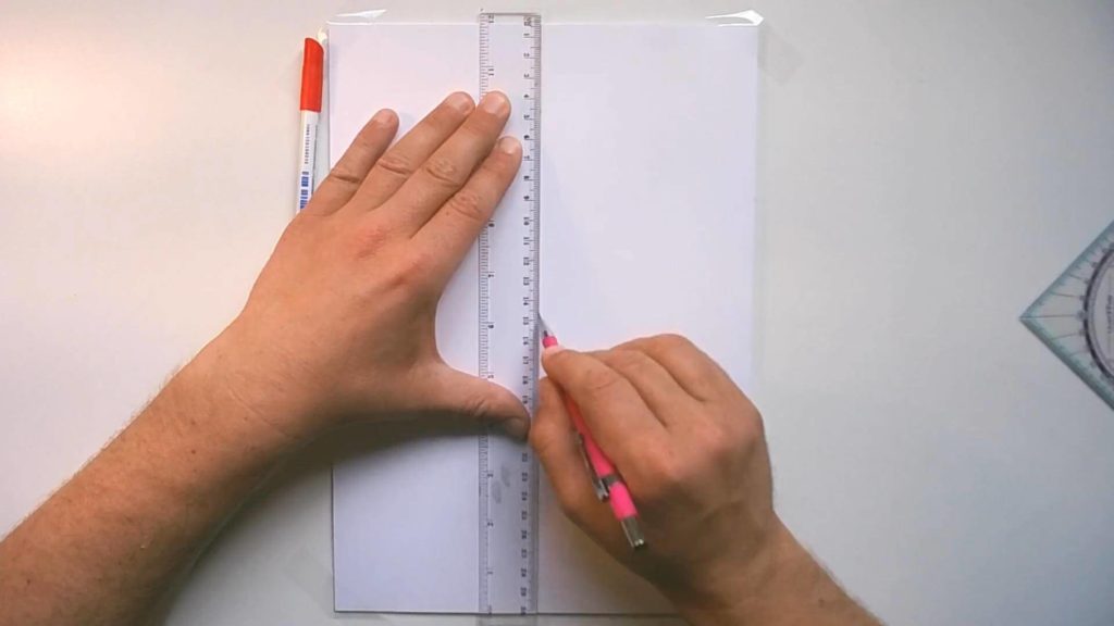 Bild von einem Papier + Lineal + Bleistift in dem Hochkant eine Senkrechte eingezeichnet wird.